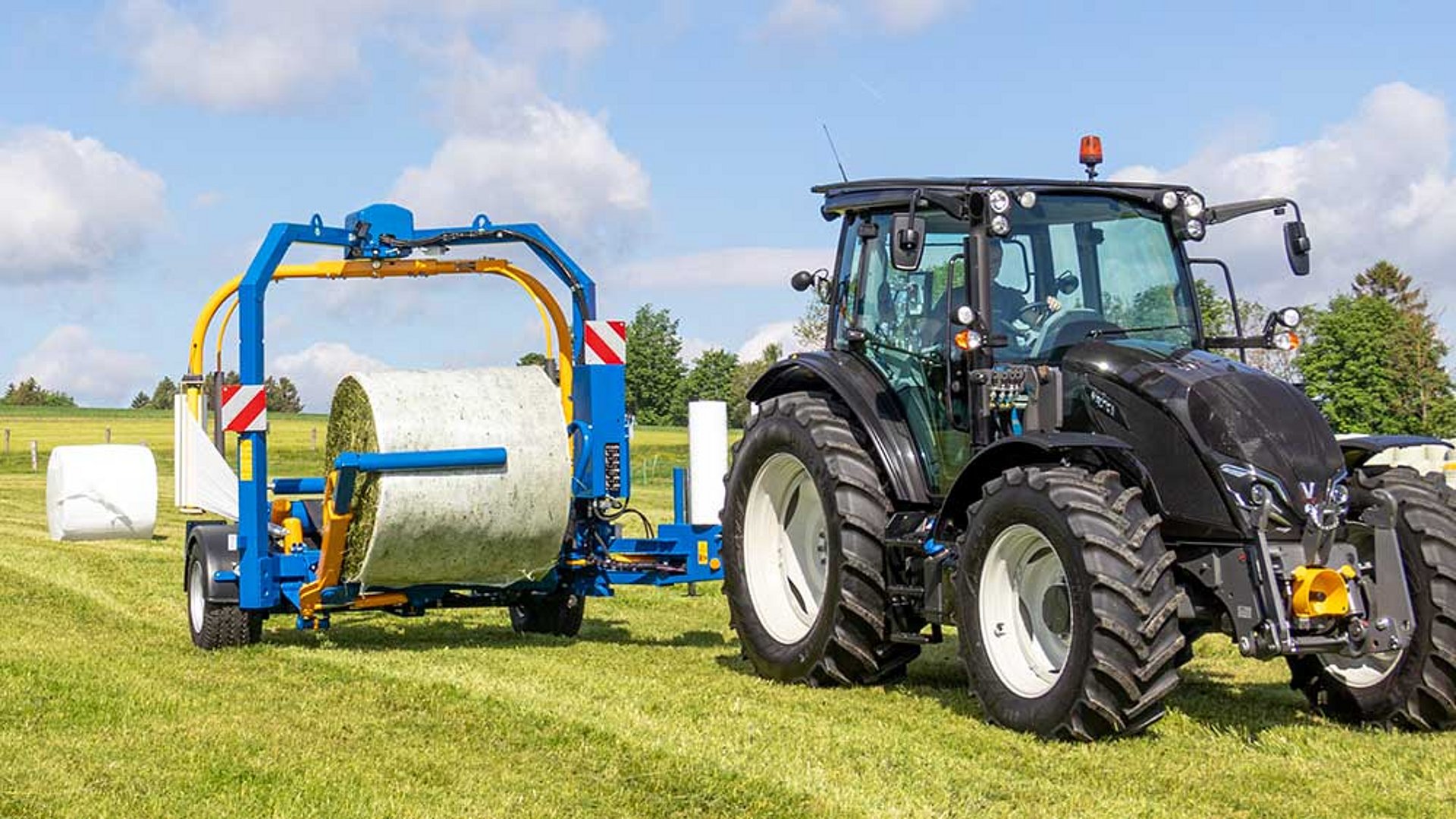 Der Wickler wird zu Beginn in Arbeitsposition, rechts versetzt hinter dem Traktor, ausgeschwenkt.
