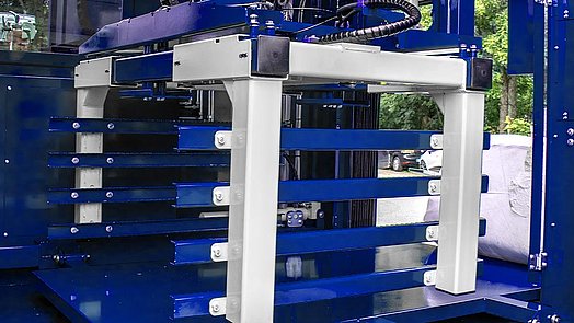 The bale manipulator recognizes the bale, grabs it and lifts it onto the wrapping table.