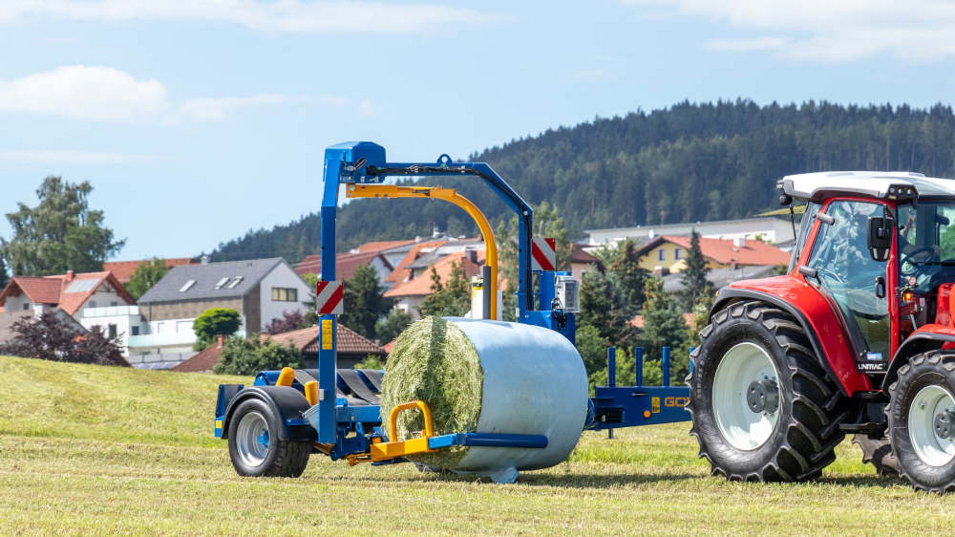 Le bras de chargement hydraulique avec le tube de prise se place sous la balle et la soulève sur la table d’enrubannage.