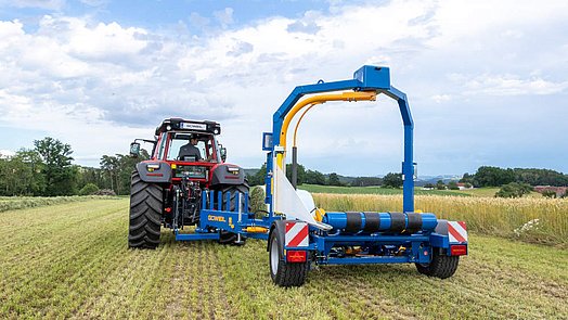 De wikkelaar wordt aan het begin in de werkpositie, rechts verspringend achter de tractor, naar buiten gezwenkt.