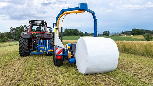 When the bale is dropped, the wrapping table is swung to the rear and lowered all the way to the ground.