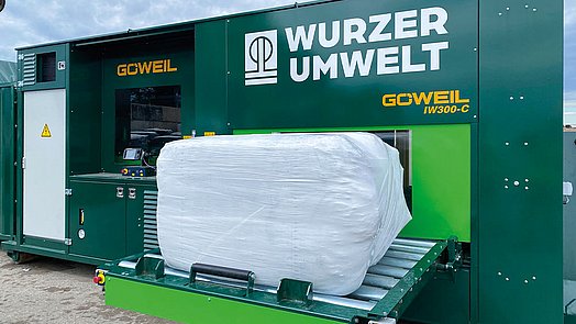 The finished bale is deposited on the hydraulically pivoting conveyor belt for removal.