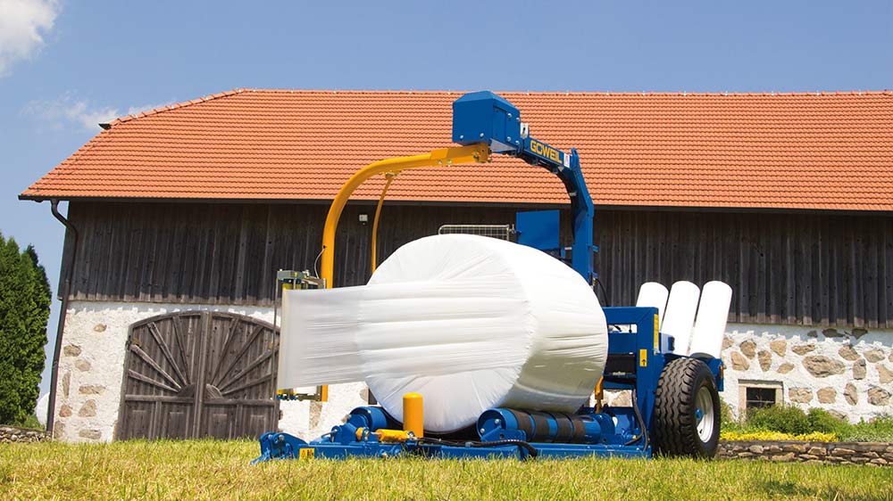 De G3010 Farmer bij het wikkelen van een ronde baal.