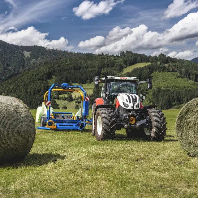 🇦🇹 Der hydraulische Ladearm greift den Ballen schonend auf und legt ihn sanft auf den Wickeltisch, dieser ist bei der Ballenaufnahme leicht nach vorne gekippt. 
Der Ladearm lässt sich in fünf verschiedenen Positionen justieren und ist somit stets perfekt an den Ballendurchmesser angepasst. Das Aufnahmerohr ist kugelgelagert und drehbar, der Ballen wird weder geklemmt noch beschädigt. Eine sichere Ballenaufnahme ist in jedem Gelände garantiert. Als besonders praktisch erweist sich der Ballenaufnehmer auch beim Transport von zwei Ballen. 😉
_____________________________________________

🇬🇧 The hydraulic loading=